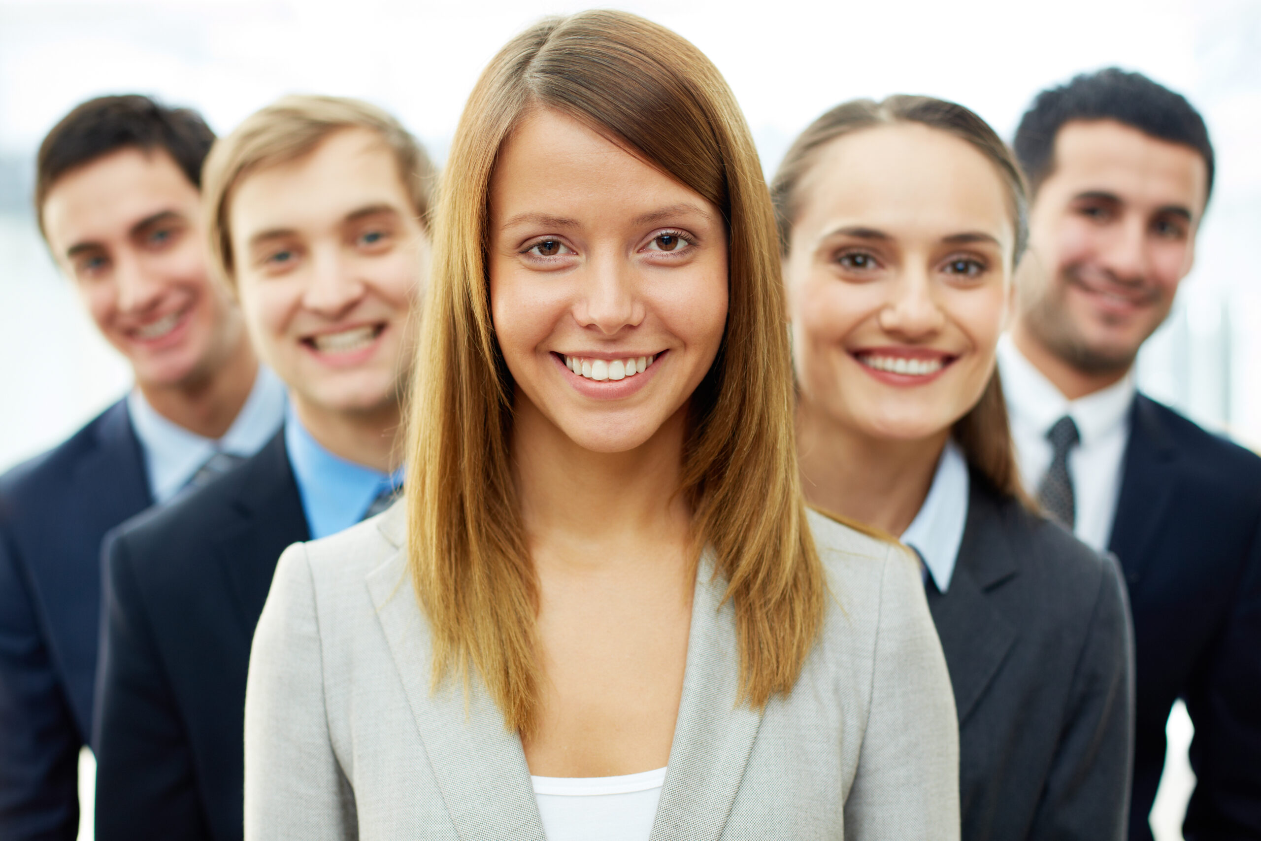 Happy businesswoman looking at camera with smart associates behind