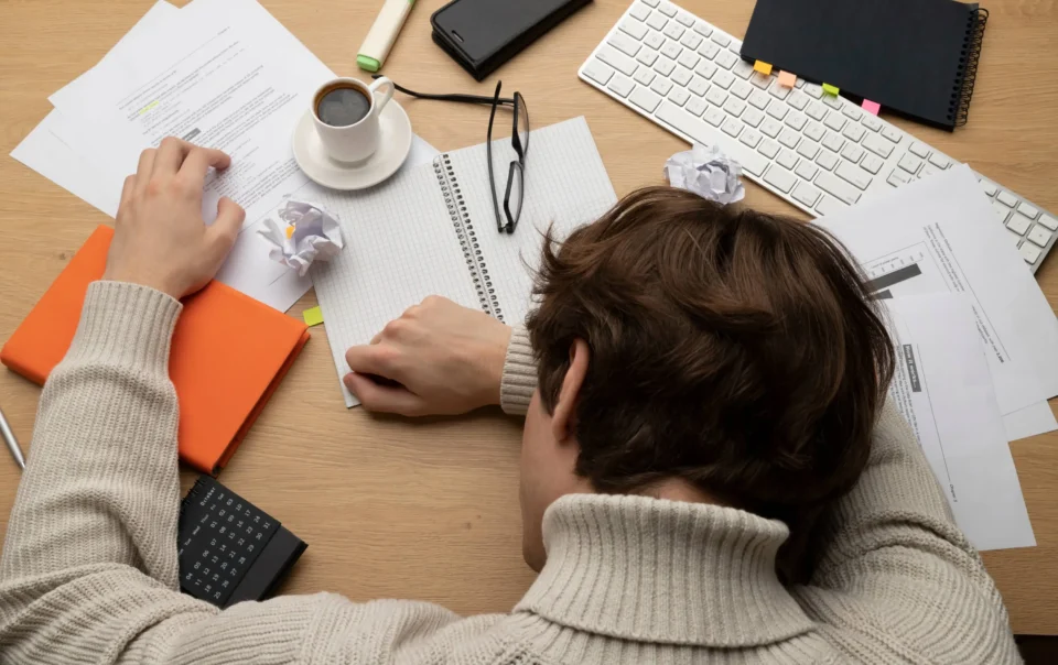 läbipõlemise tunnused: kurnatud inimene laua taga pea kätele toetatud